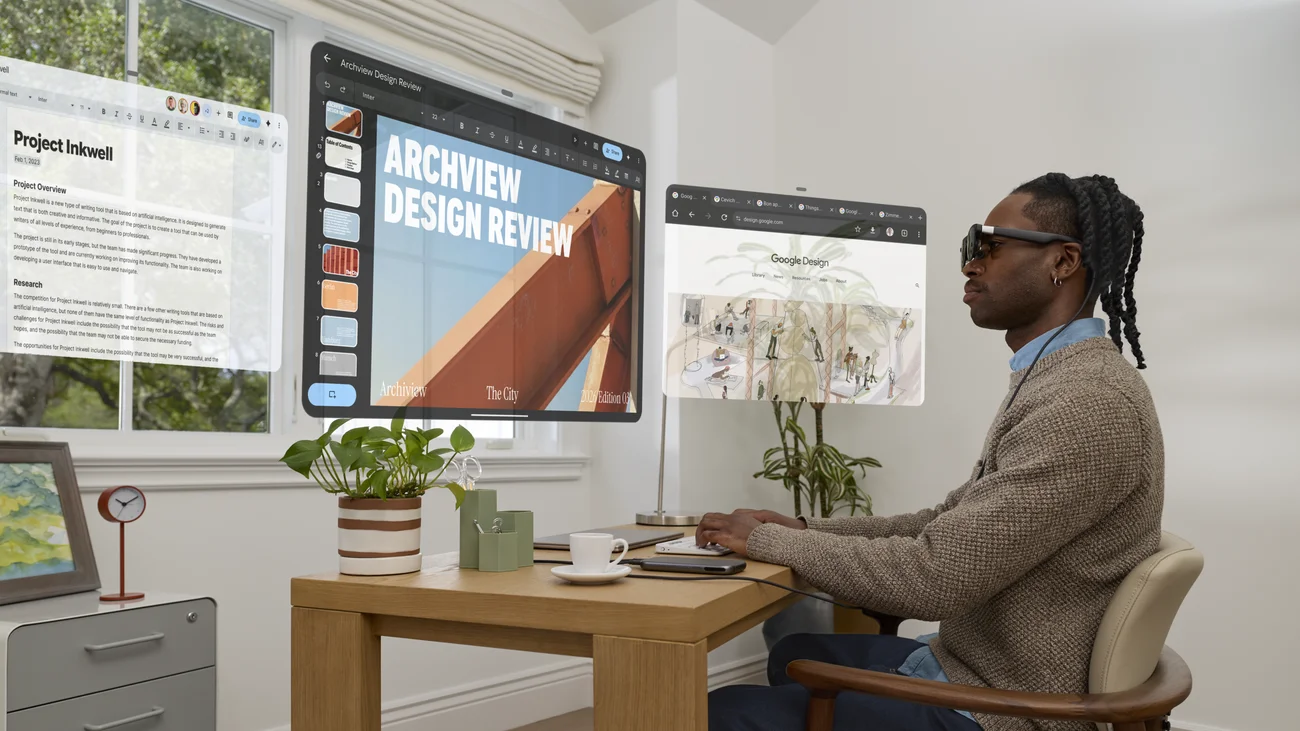 Person wearing XREAL AURA Android XR glasses in an office workspace.