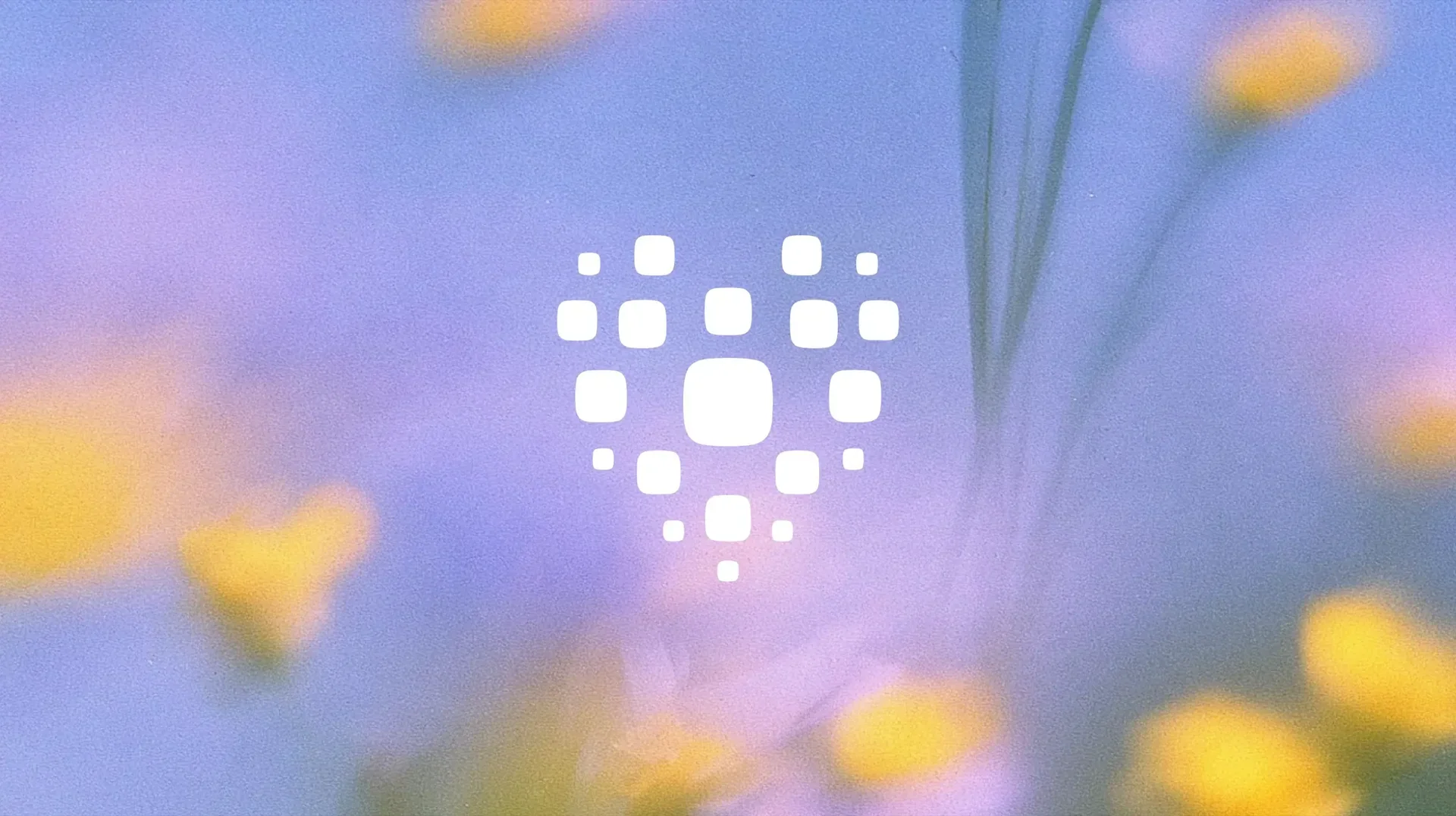 Heart-shaped cluster of rounded white squares over a soft-focus purple and yellow floral background