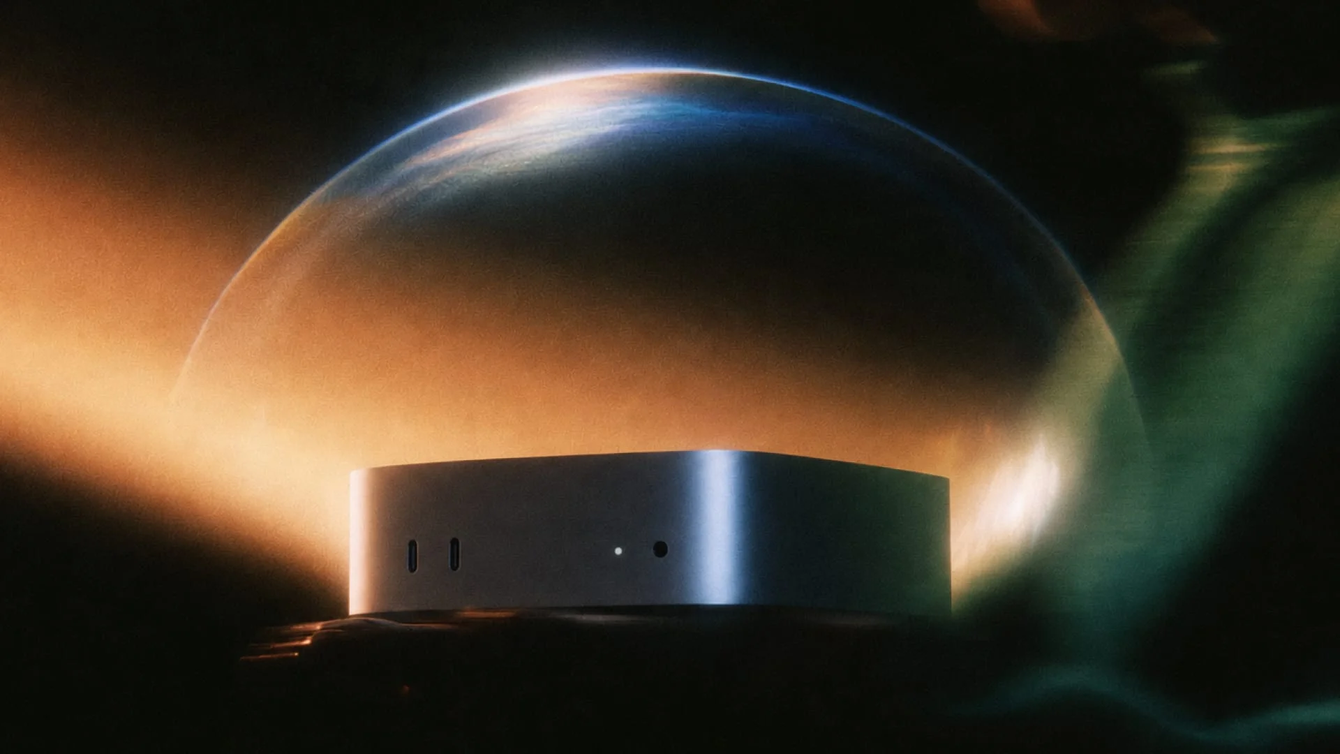 A silver Mac mini on a dark surface, with a glowing arc like a planet’s edge behind it