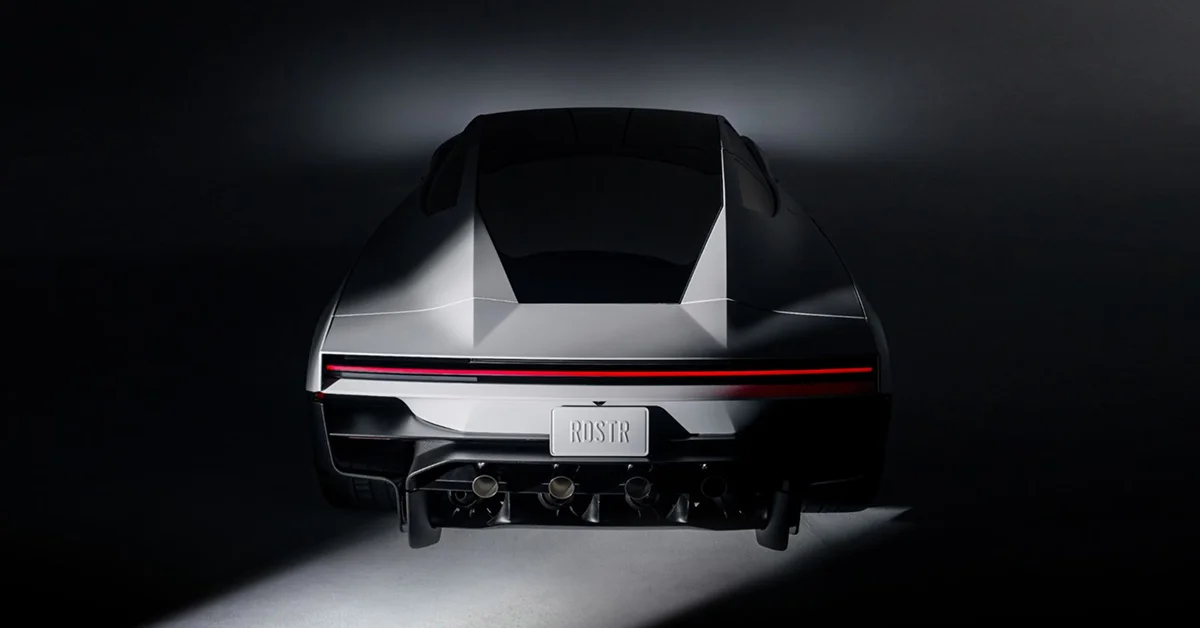The rear of a silver Tesla Roadster in a dark studio, with a full-width red taillight, an “RDSTR” number plate and four round nozzles under the bumper